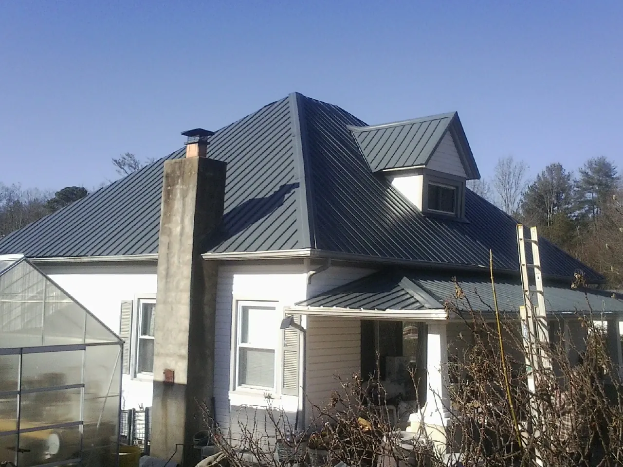 Dark blue standing seam metal roof on a white farmhouse with dormer — Slate & Tile Roof Repair by Roofing Brothers in Duchesne