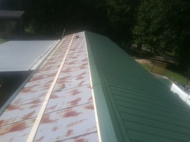 Old rusted panels beside newly installed green metal roofing — Wind Damage Roof Repair by Roofing Brothers in Duchesne
