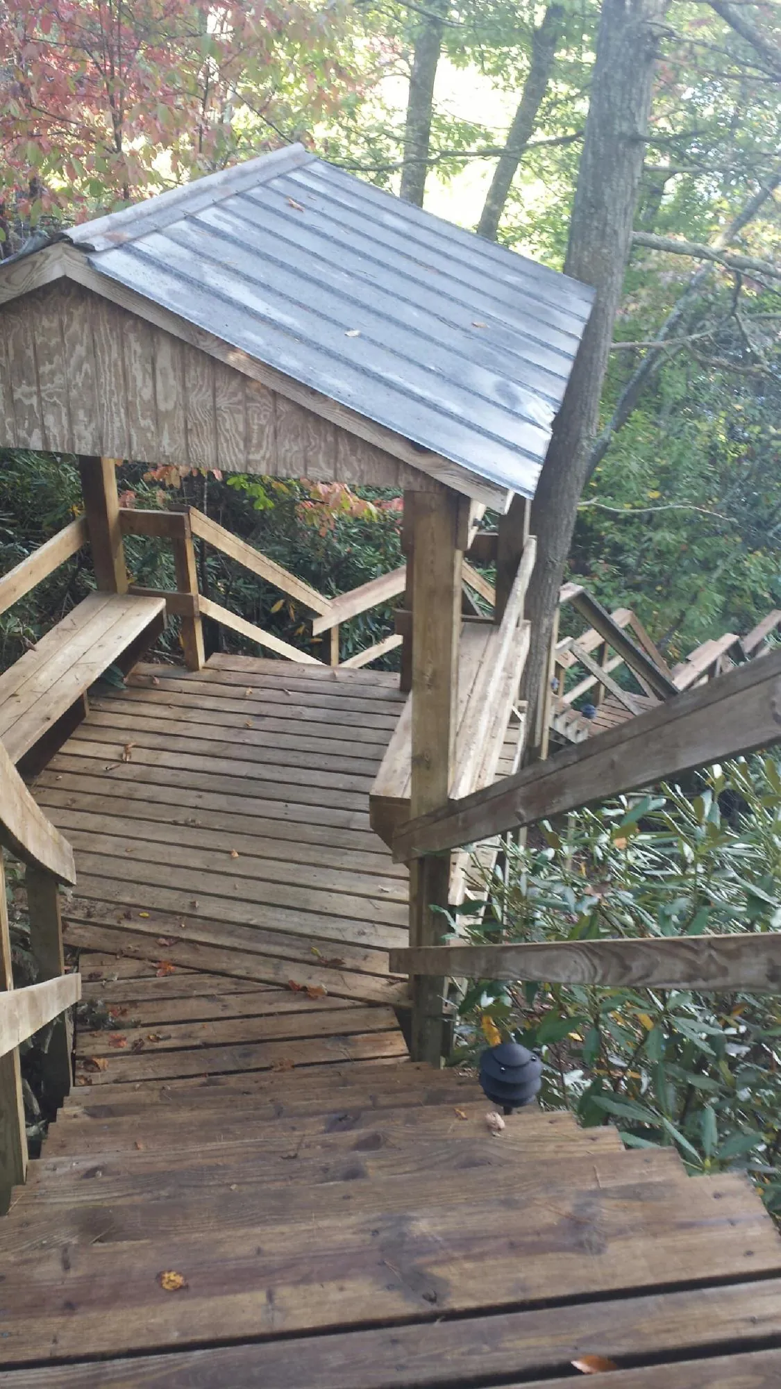 Metal roofed shelter over wooden steps on a wooded walkway — Skylight Repair & Installation work by our crew in Duchesne