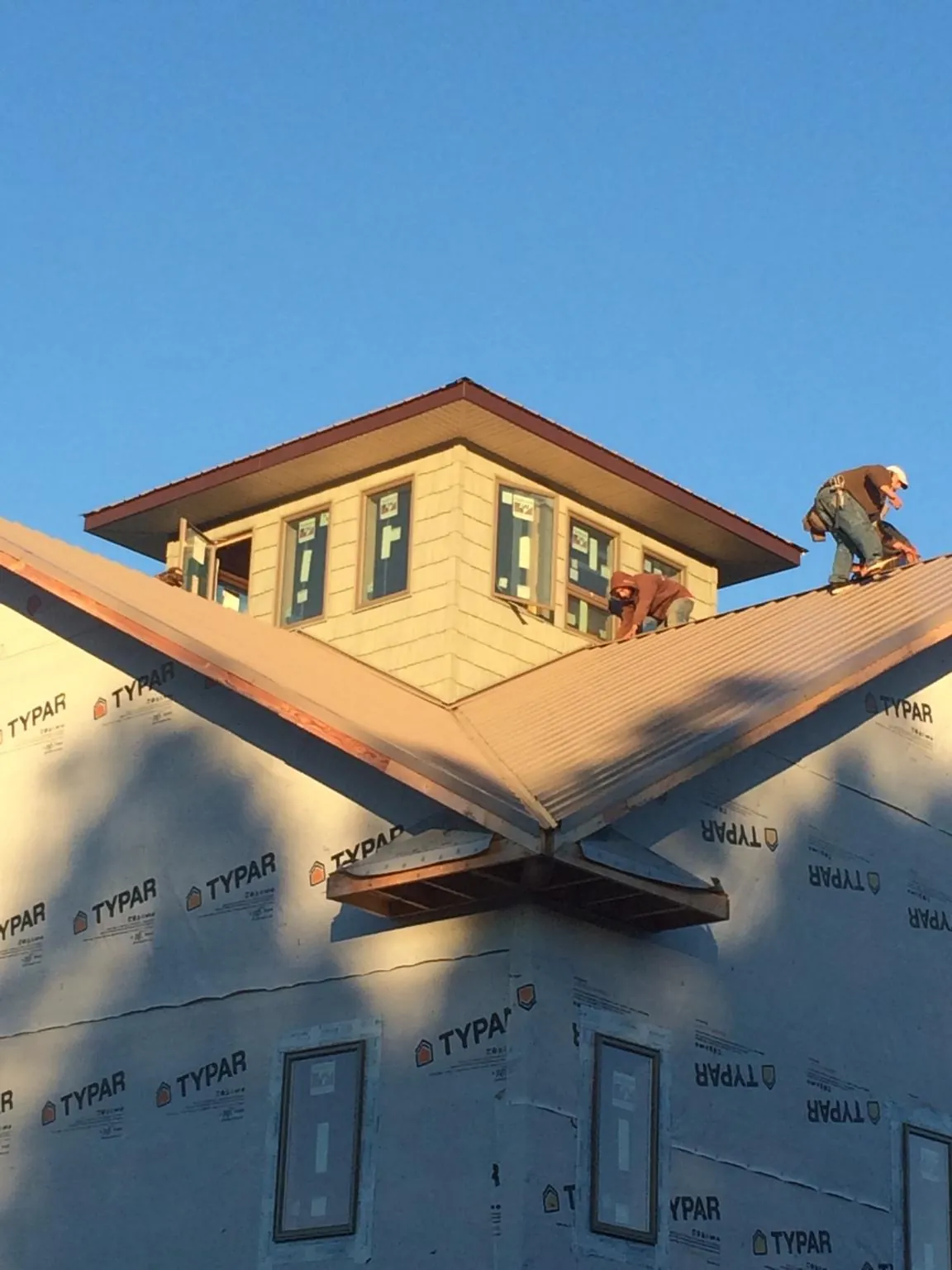 Roofers working around a rooftop cupola on a new metal roof at sunset — Roof Waterproofing in Duchesne by Roofing Brothers